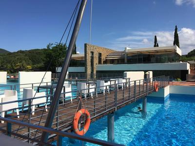 Hölzerne Brücke mit Lebensring über blauem Hotelpool und klar blauem Himmel