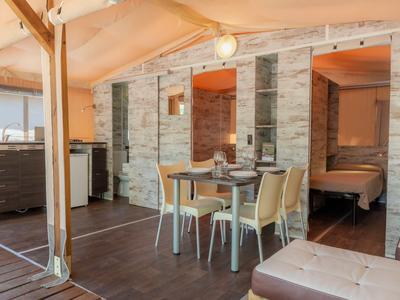 Moderner Essbereich in einem Hotelzimmer mit Holzbalken und Blick auf Schlafzimmer.