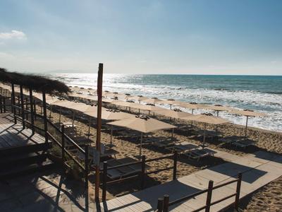 Playa con olas, arena y sombrillas en un día despejado