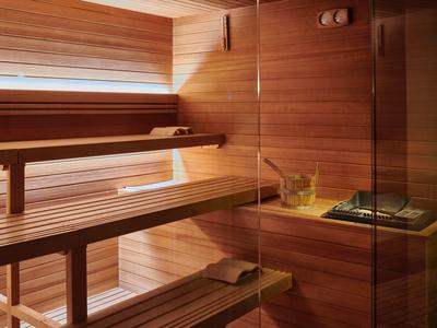 Drewniana sauna z wielopoziomowymi ławkami i piecem w przytulnej atmosferze.