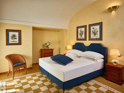 Przytulny pokój hotelowy z podwójnym łóżkiem, drewnianymi meblami i ciepłym oświetleniem.