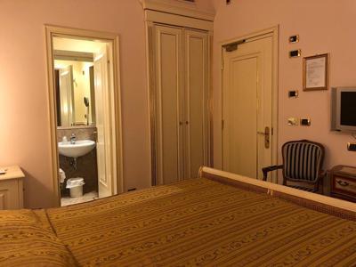 Hotel room with double bed, wardrobe, sink, and chair by the wall