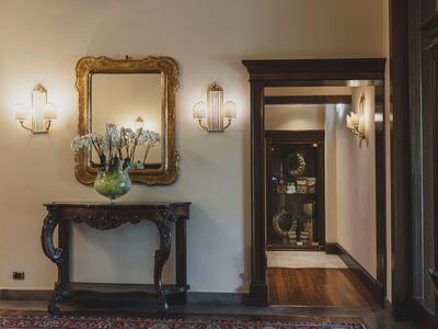An elegant hallway with an antique table, mirror, and wall lamps in a hotel.