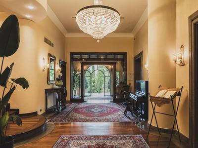 Elegant hotel hallway with chandelier, rugs, and view of garden doors.