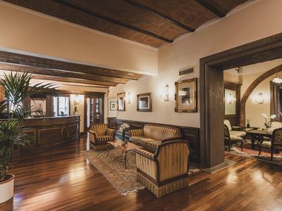 Elegant hotel lounge area with wooden floor, cozy armchairs, and warm lighting.