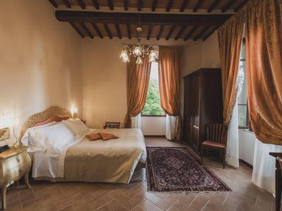 Elegantes Hotelzimmer mit Holzbalkendecke, Doppelbett, Teppich und Vorhängen.