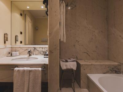 Modernes Hotelbadezimmer mit Doppelwaschbecken, Handtüchern und Duschbadewanne aus Marmor.