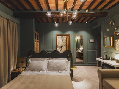Schlafzimmer mit Doppelbett, Holzbalkendecke und warmem, gedämpftem Licht in einem Hotel.
