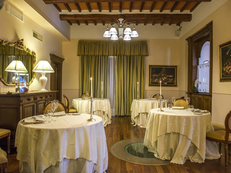 Elegant dining room with round, white-covered tables in a traditional style.