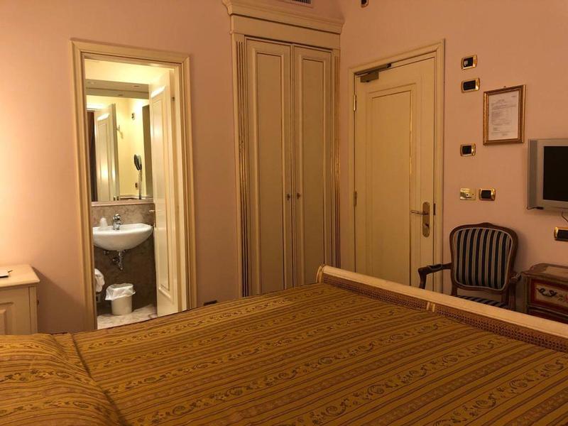 Hotel room with double bed, wardrobe, sink, and chair by the wall