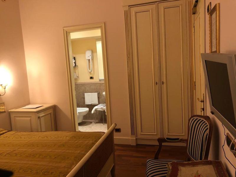 Cozy hotel room with double bed, nightstand, mirror, wardrobe, and TV.