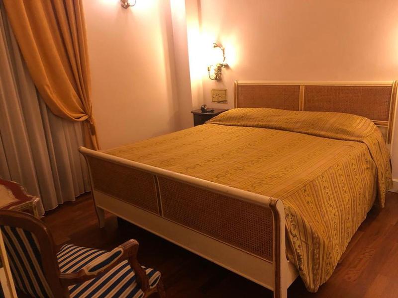 Cozy bedroom with large bed, orange curtains, and wooden floor.