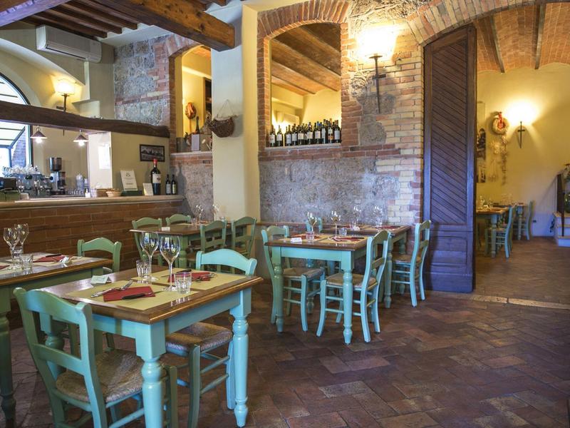 Cozy restaurant with wooden tables, green chairs, and warm lighting.