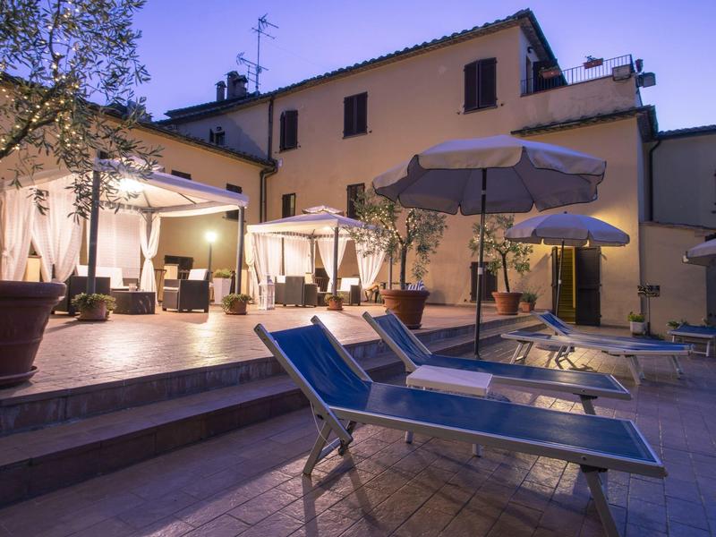 Przytulny taras z leżakami i parasolami przy hotelu wieczorem.