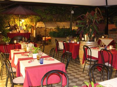 Cozy restaurant with red-covered tables and chairs in a green courtyard.