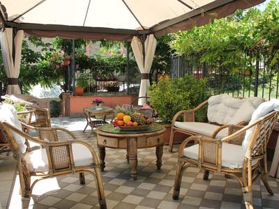 Cozy patio with chairs and table under tent, surrounded by green plants.