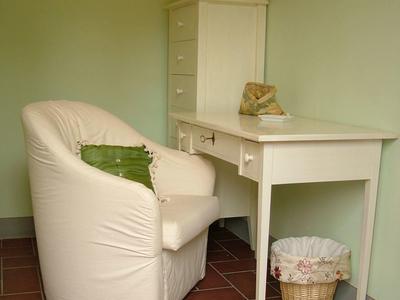 White desk with a cushioned chair and cactus in a calm green-toned room.