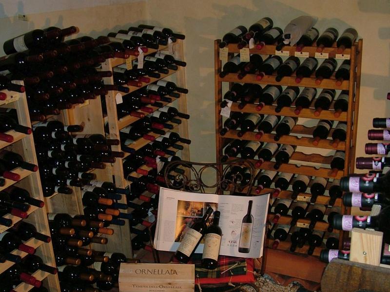 Wine cellar with multiple racks filled with wine bottles in a room with a vaulted ceiling.
