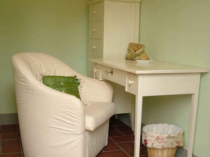 White desk with a cushioned chair and cactus in a calm green-toned room.