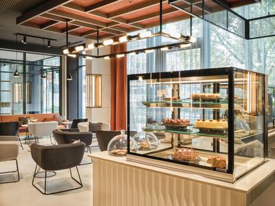 Moderne Hotellounge mit stilvollen Sesseln und einer Vitrine voller Gebäck.