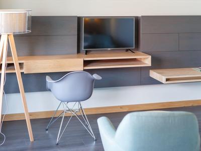 Espacio de trabajo moderno con escritorio, silla, lámpara de pie y televisor en tonos neutros.