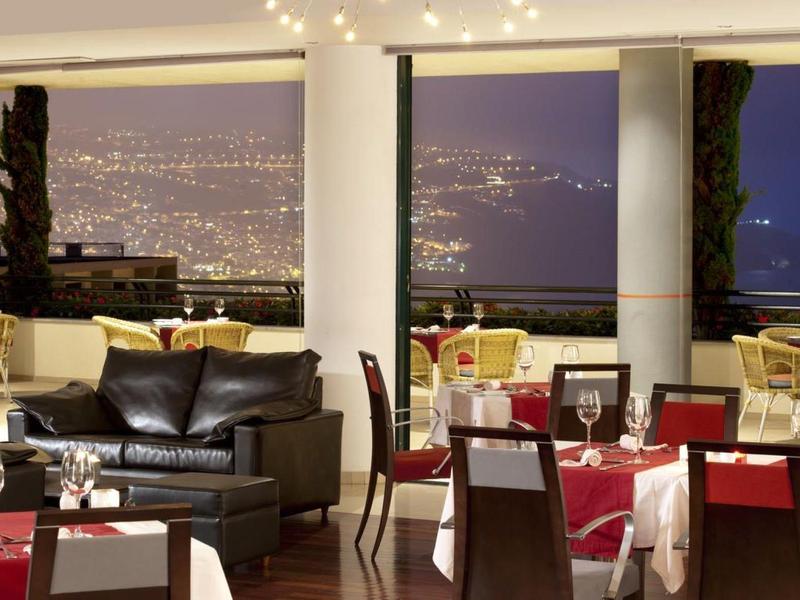 Restaurante elegante con vista a las luces de la ciudad y un sofá de cuero cómodo junto a la ventana.