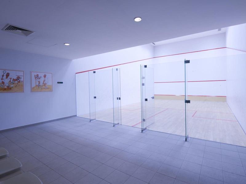 Sala de fitness moderna y luminosa con pared de espejos y sillas alineadas en una pared.