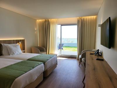 Hotelový pokoj se dvěma postelemi, televizí, balkonem s výhledem na moře a posezením.