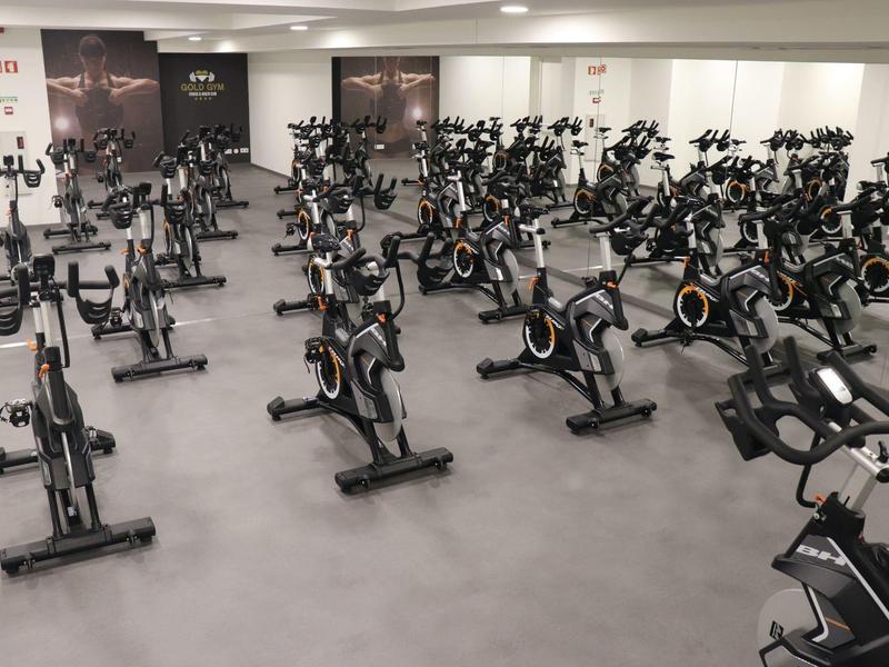 Velká posilovna s mnoha stacionárními jízdními kola a světlými stěnami.