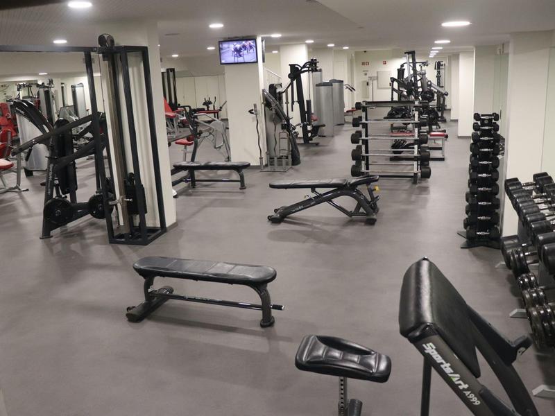 Světla, moderní posilovna se stroji a volnými váhami.