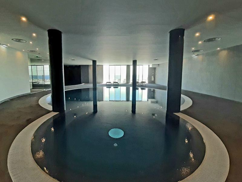 Moderní kulatý vnitřní bazén s sloupy a podlahovým osvětlením v hotelu