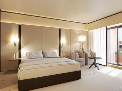 Modernes Hotelzimmer mit Doppelbett, zwei Sesseln, Nachttischen und Balkon mit Glaswand.