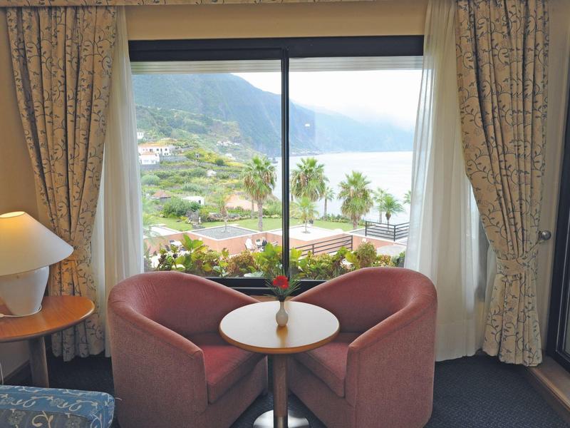 Cozy seating area by panoramic window overlooking mountains and water