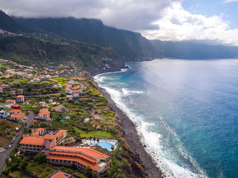 Coastal landscape with hotels, beach, and clear blue water under a cloudy sky.