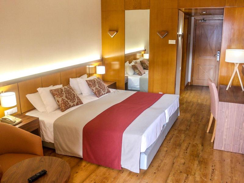 Comfortable hotel room with double bed, wooden furniture, and cozy reading chair.