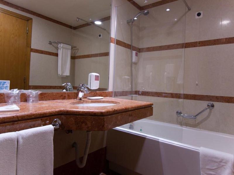 Modern hotel bathroom with bathtub, sink, and towels.