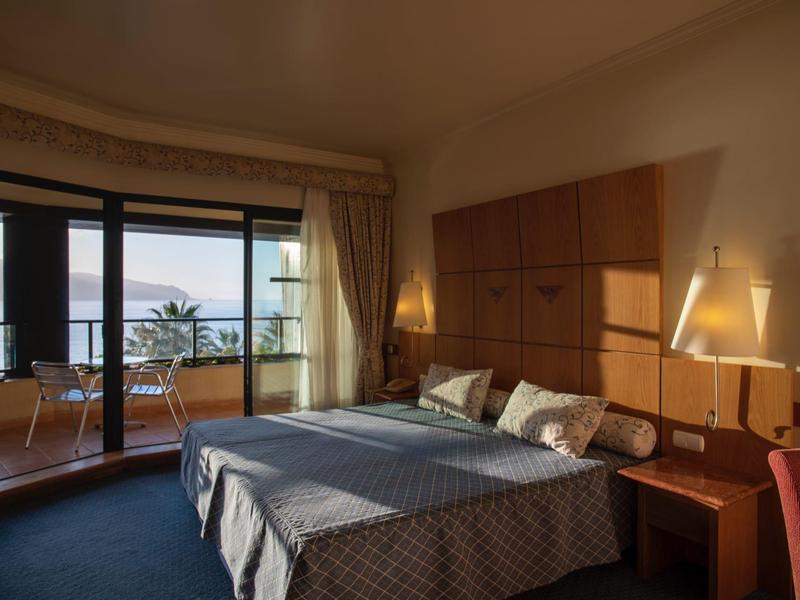 Cozy hotel room with double bed and balcony overlooking the sea.