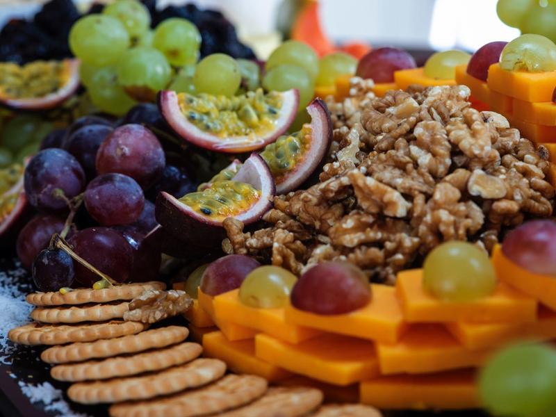 Appetizer platter with cheese, grapes, walnuts, crackers, and passion fruit.