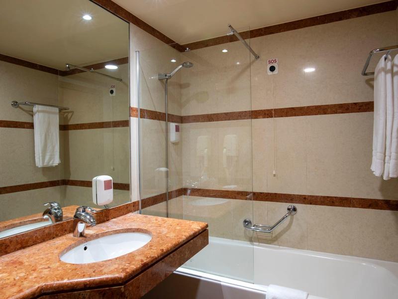 Modern bathroom with bathtub, sink, and large mirrors in a hotel.