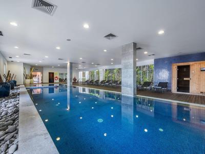 Innenbereich mit langem Schwimmbecken, blauen Fliesen, Sitzecke und Sauna in modernem Design.