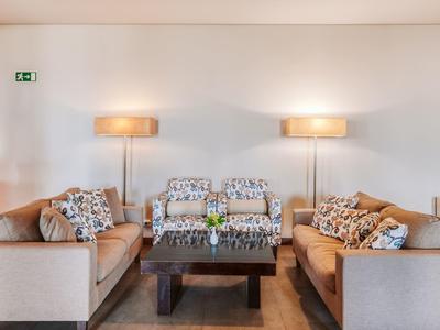 Modern eingerichtetes Wohnzimmer mit zwei Sofas, gemusterter Polsterung, Holz-Couchtisch und Stehlampen.