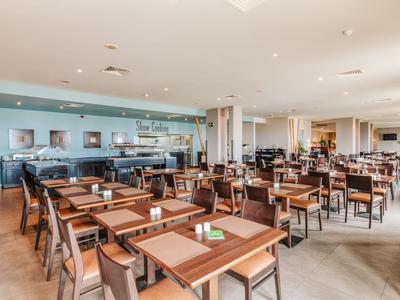 Geräumiges Restaurant mit braunen Holztischen und bequemen Stühlen, modernes und helles Ambiente.