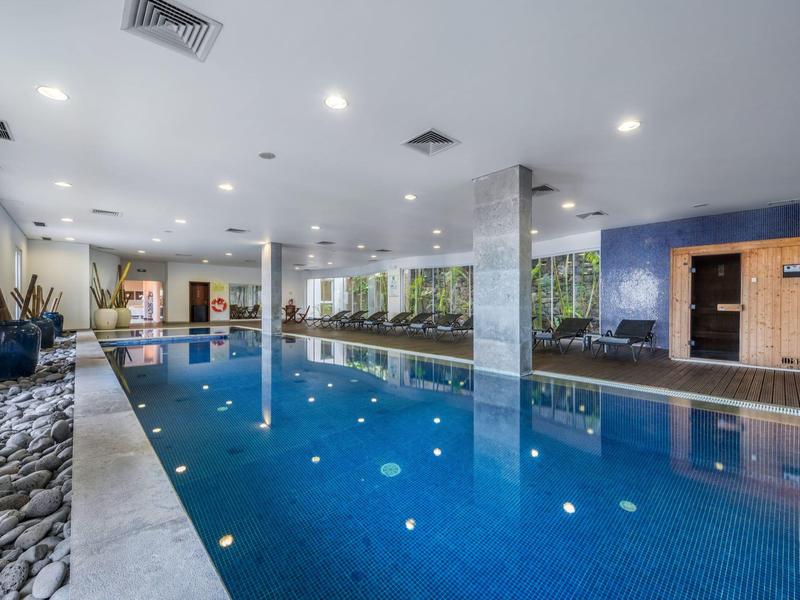 Modern indoor pool with sauna and cozy lighting in a hotel.