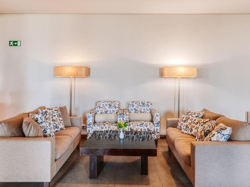 Cozy seating area with two sofas, lamps, and a black coffee table in a hotel room.