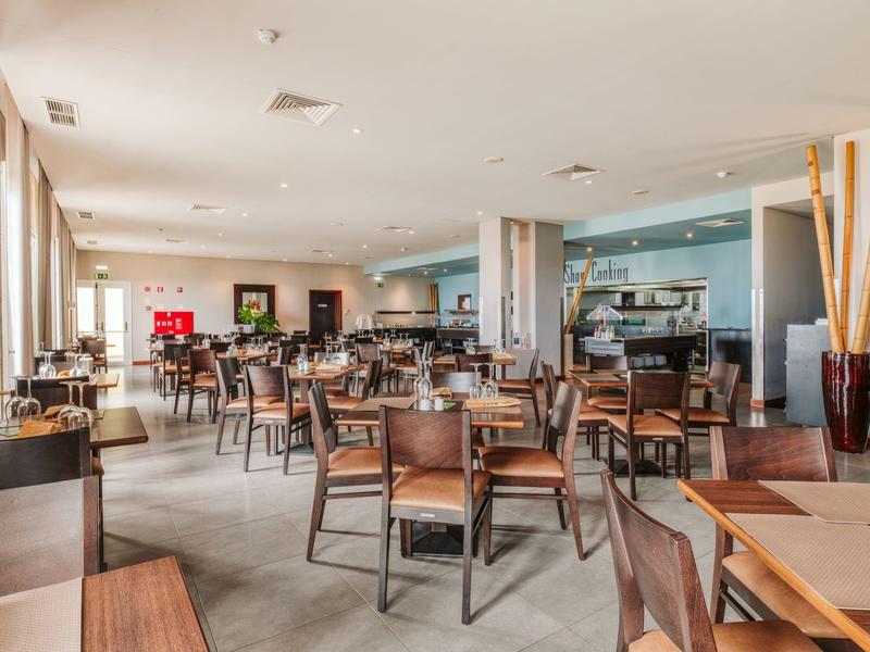 Bright restaurant with many wooden tables and chairs, modern decor and large windows.