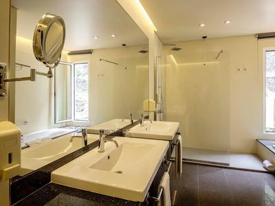 Helles Badezimmer mit zwei weißen Waschbecken, Spiegel und Fenster, moderne Schlichtheit.