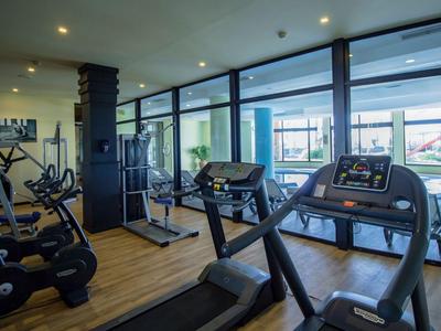 Moderner Fitnessraum mit Laufbändern, Fahrrädern und großen Fenstern mit Blick nach draußen.