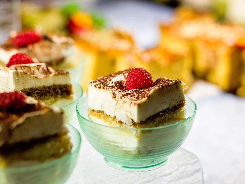 Mehrere kleine Gläser mit Schichtdessert, oben mit Himbeere und Schokoraspeln dekoriert.