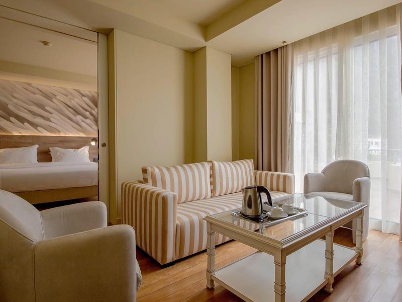 Gemütliches Hotelzimmer mit Sofas, Sessel und großem Fenster mit Vorhängen.