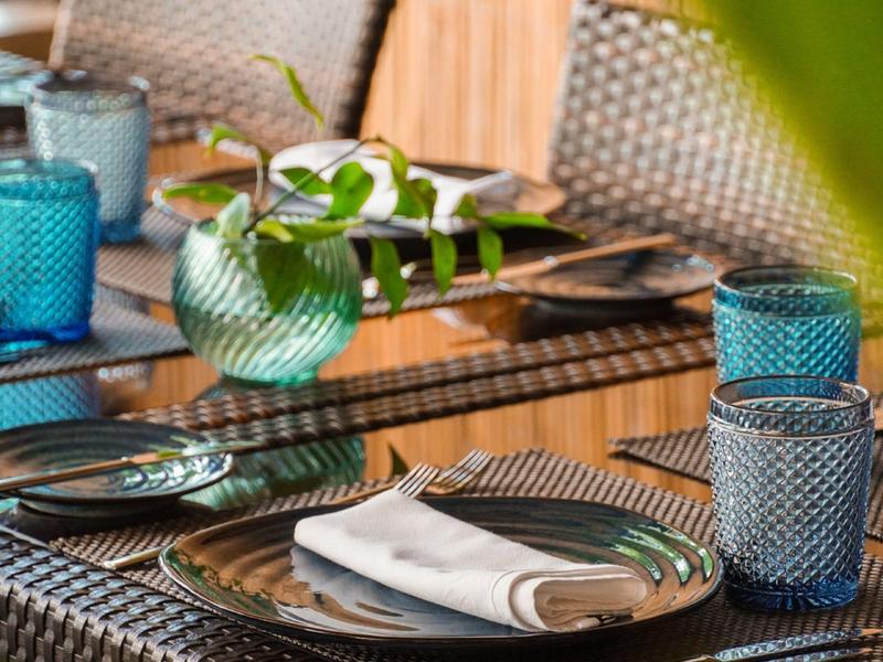 Dekorierter Holztisch mit blauem Geschirr und grüner Pflanze in modernem Essbereich.